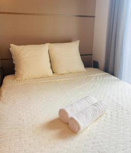 a white bed with two pillows and a pair of towels at Cocoon break near CDG Airport & 30 min from Paris in Tremblay En France