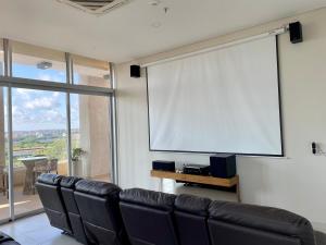a large screen in a room with leather chairs at Los laureles Loft in Asuncion