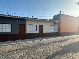a house with brown doors and a cobblestone street at Recanto Mandacaru in Queimada