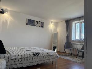 a bedroom with a bed and a chair and a window at MIK Chalet in Săcele