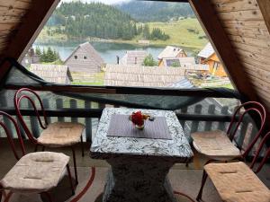 a table and chairs in a room with a large window at Vikendica Litrić in Fojnica