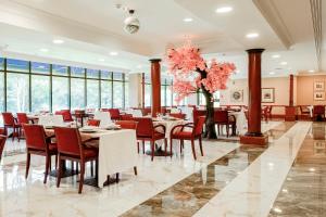 a dining room with tables and chairs and pink flowers at Muthu Glasgow River Hotel in Erskine