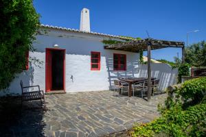 a white house with a red door and a table at Aldeia da Pedralva by WOT Signature in Vila do Bispo
