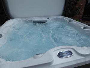 a jacuzzi tub with blue water in it at Falstaff Cottage, NEW HOT TUB, Sleeps up to 5, Stratford upon Avon in Stratford-upon-Avon