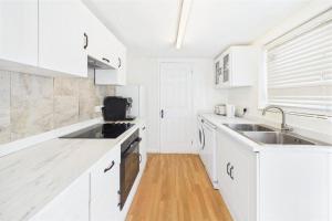 a white kitchen with white cabinets and a sink at 3 Bed House in Reading Area in Reading