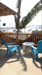 a patio with two chairs and a table and a palm tree at Casa de Heidi in Puerto López