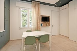 a dining room with a white table and green chairs at La Casina di Luca in Rimini