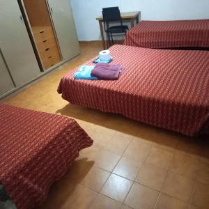a room with three beds with red sheets and a table at Hotel Florentino in Buenos Aires +10 photos