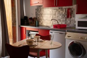 a kitchen with red cabinets and a table and a sink at L'Echappée Romane in Saint-Nectaire