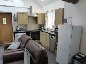eine Küche mit einem Sofa und einem weißen Kühlschrank in der Unterkunft Romeo Cottage - Sleeps 4 - Open Plan Barn - Private Hot Tub & Garden in Stratford-upon-Avon