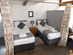 1 Schlafzimmer mit 2 Betten mit Vorhängen und einem Tisch in der Unterkunft Romeo Cottage - Sleeps 4 - Open Plan Barn - Private Hot Tub & Garden in Stratford-upon-Avon