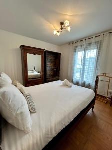 Schlafzimmer mit einem großen weißen Bett und einem Spiegel in der Unterkunft Maison calme avec jardin & terrasses 