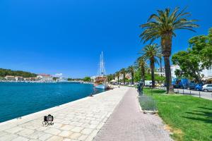 una acera junto a un cuerpo de agua con un barco en Apartments Marieta, en Makarska