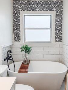 une baignoire blanche dans une salle de bains avec fenêtre dans l'établissement Heritage House, à Brady 8 autres photos