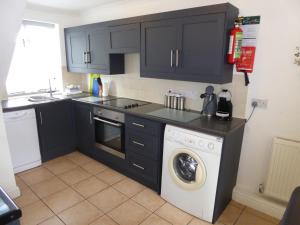 a kitchen with black cabinets and a washing machine at Juliet Cottage HOT TUB Sleeps 3 Singles or Double in Stratford-upon-Avon