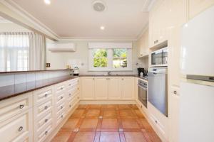 a large kitchen with white cabinets and a window at Porters Cottage Grande (two units) in Albury