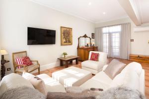 a living room with a white couch and a tv at Porters Cottage Grande (two units) in Albury