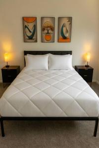 a bedroom with a large white bed with three pictures on the wall at 4BR Luxury, Walk to Old Town, Arcade, Pool, 12 Guests in Scottsdale