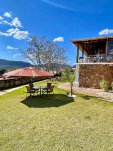 a picnic table with an umbrella in the grass at Pousada Varandinha in Tiradentes