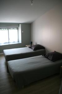 two beds sitting in a room with a window at Gîte du Four Banal in Louin