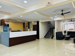 a lobby with a counter and chairs and a staircase at Hotel PANDIT PALACE in Visakhapatnam