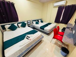 two beds in a room with a red chair at Hotel PANDIT PALACE in Visakhapatnam +35 photos