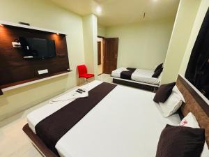 a hotel room with two beds and a flat screen tv at Hotel PANDIT PALACE in Visakhapatnam