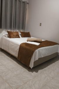 a bedroom with a bed with brown and white sheets and pillows at Village Prime in Inocência