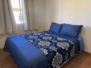 a blue bed with a blue comforter and a window at Canoas Ulbra Parkshopping in Canoas