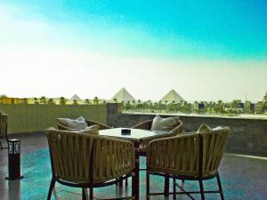 a patio with a table and chairs and pyramids at Galleria Hotel Pyramids View in Cairo