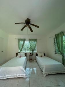 two beds in a room with a ceiling fan at Modern mountain house in Anchovy Station +63 photos
