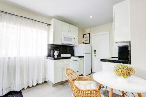 Una cocina con gabinetes blancos y una mesa con sillas. en La Moderna - A Private Guesthouse, en Hollywood