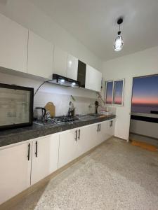 a kitchen with white cabinets and a microwave at Sunset Vibes Larache in Larache