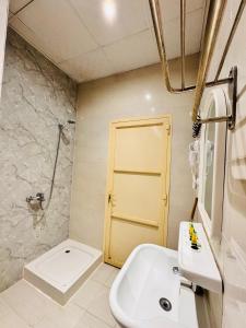 Un baño con lavabo, inodoro y puerta. en رفاء الذهبية للشقق المخدومة, en Al Makhwāh