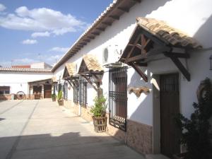 ein weißes Gebäude mit einem Tor und einem Zaun in der Unterkunft Apartamentos Venta Don Quijote in Almagro