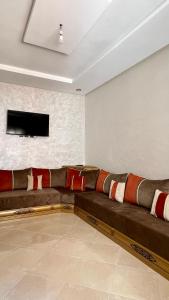 a large couch in a room with a tv on a wall at Appartement Agadir in Inezgane