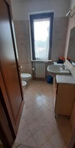 Un baño con lavabo, inodoro y ventana. en la casa di Camilla, en Volvera