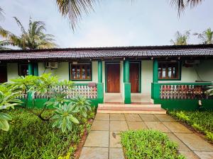a green house with a pathway in front of it at Golden Pearl Beach Resort in Baga
