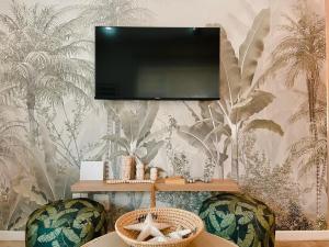 a living room with two chairs and a television on a wall at Coastal Bliss Lodge with Direct Beach Access in Ballito