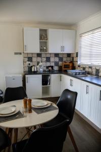 eine Küche mit weißen Schränken und einem Tisch und Stühlen in der Unterkunft Willowdale Farm Cottage 2 in Nottingham Road + 6 Fotos