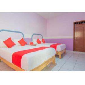 a bedroom with two beds with red pillows at Hospedaje Villa Hidalgo in Villa Hidalgo