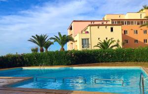 a swimming pool in front of a building with palm trees at Savanna Beach in Cap d'Agde