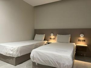 twee bedden in een kamer met witte lakens bij Viaje Hotel Downtown Cairo in Caïro