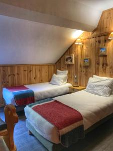 two beds in a room with wooden walls at Hôtel Quin Te Va in Cauterets +16 photos