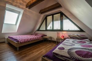 a attic bedroom with two beds and two windows at Apartment Jamy in Tatranská Lomnica