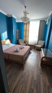 een slaapkamer met blauwe muren en een bed en een kroonluchter bij Triumph Comfort in Astana