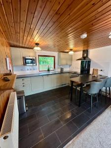 a kitchen with a wooden ceiling and a table and chairs at Craiglea Cottage in Fort William