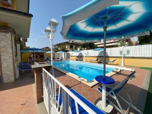 a swimming pool with a blue umbrella and a chair and a table at Miu' B&B , Ciampino , Villa con Piscina e Parcheggio Privato in Ciampino