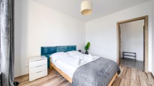 a white bedroom with a bed and a mirror at Apartament nad morzem in Kołobrzeg