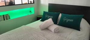 a bed with green pillows and white towels on it at Gîte Chez Erika et Mathias in Grignan +10 photos